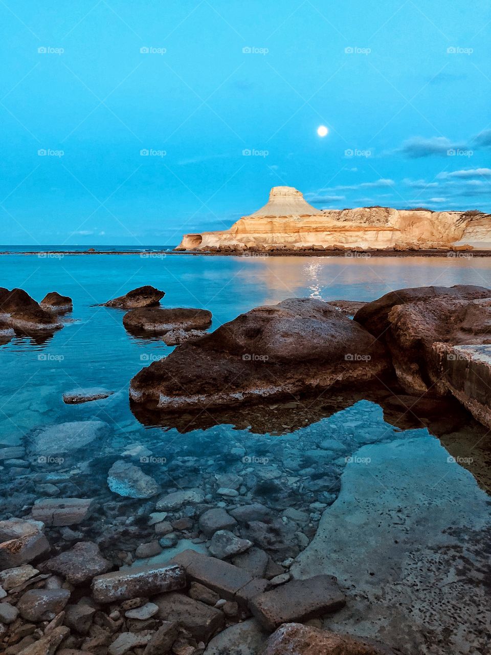 Rock formation in Xwenji Bay, on the island of Gozo. Full moon in the background.
