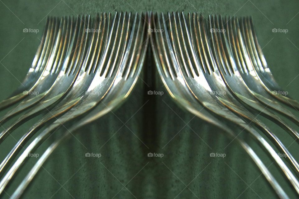 Close up of many silver forks standing on green wall 