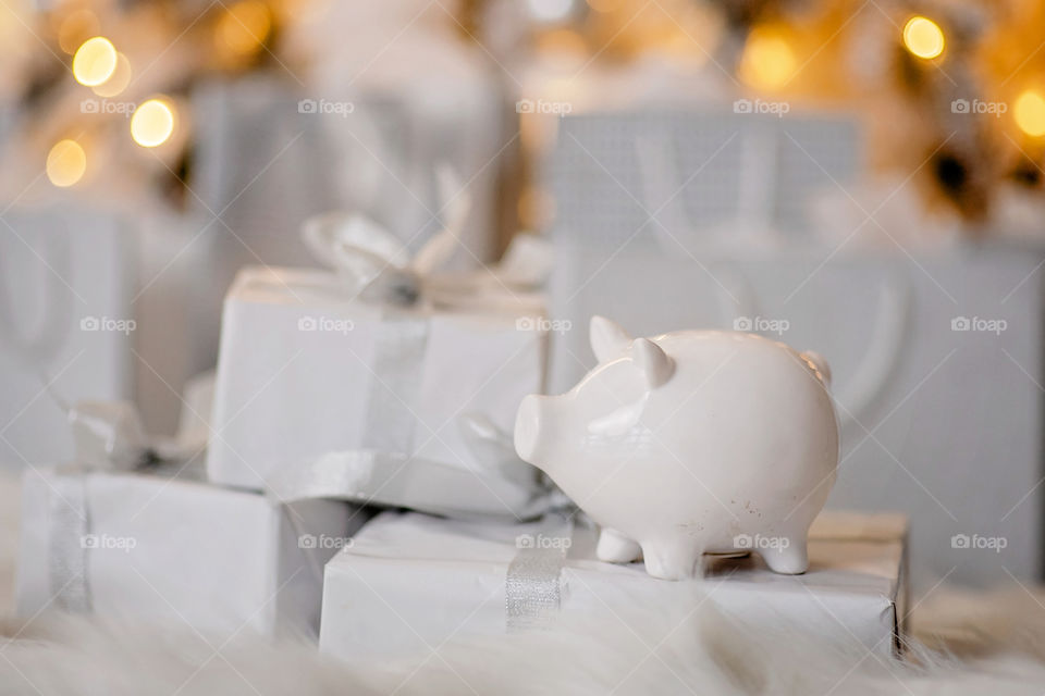 piggy bank with 100 dollars banknote in festive New Year atmosphere of scenery.  Magical bokeh with Christmas tree and bright lights.