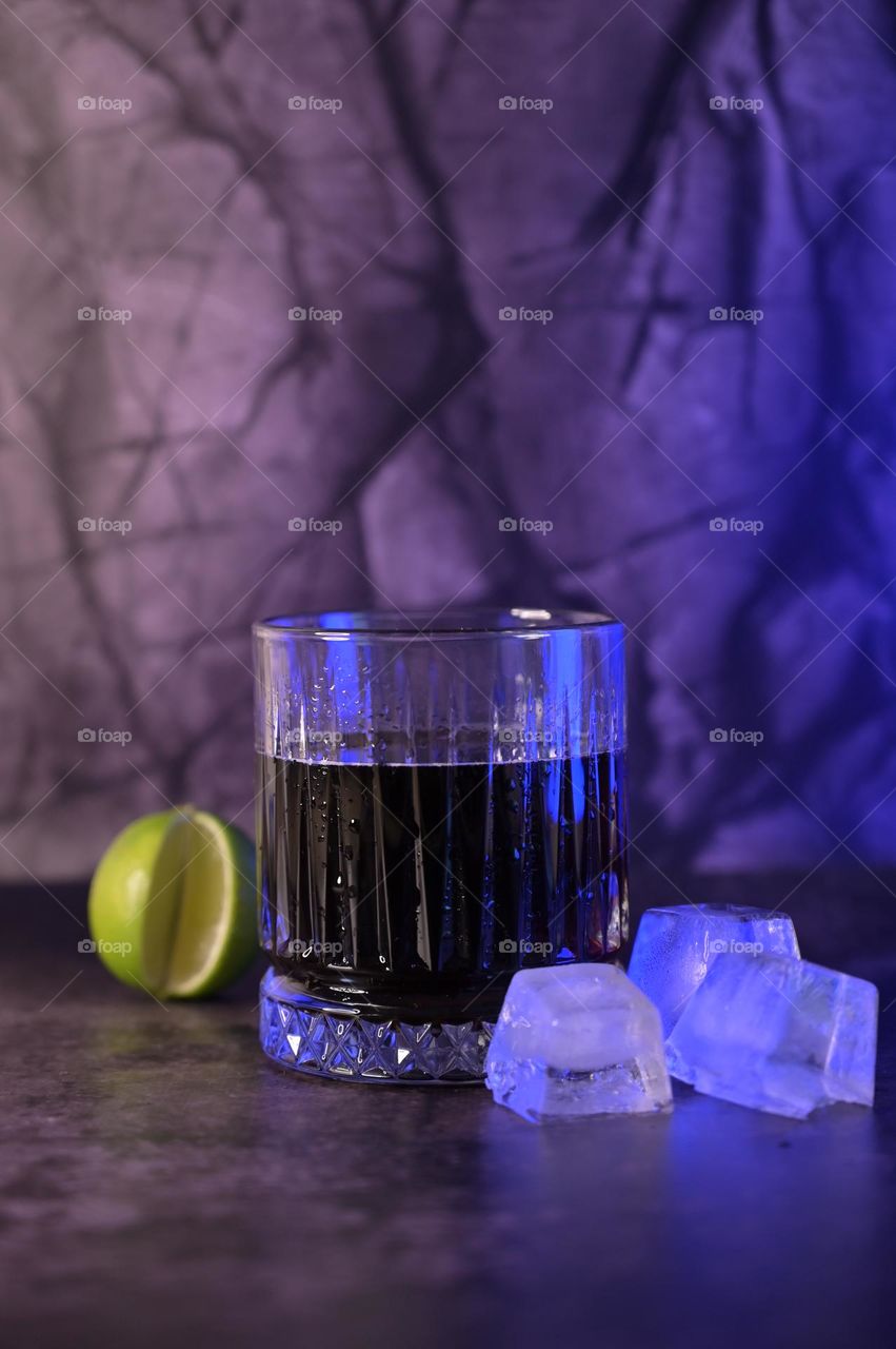 A Glass of Cold Sparkling Soda Water on Dark Background, Ice Cube and Lime Near a Glass