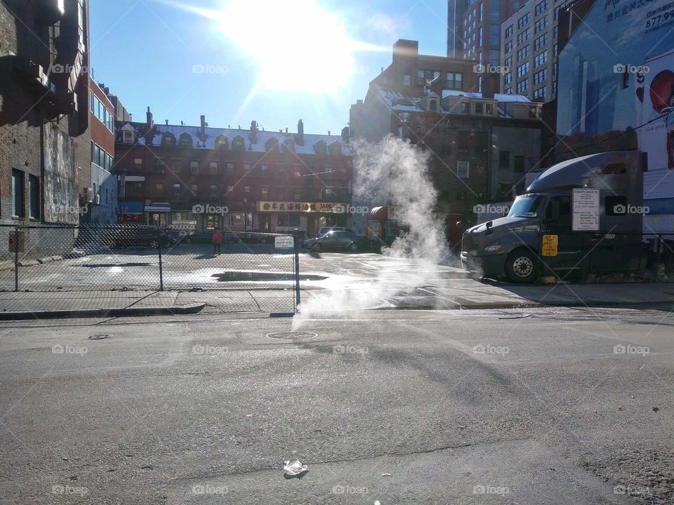 Steam gushing out from the street in Boston after a snowstorm.