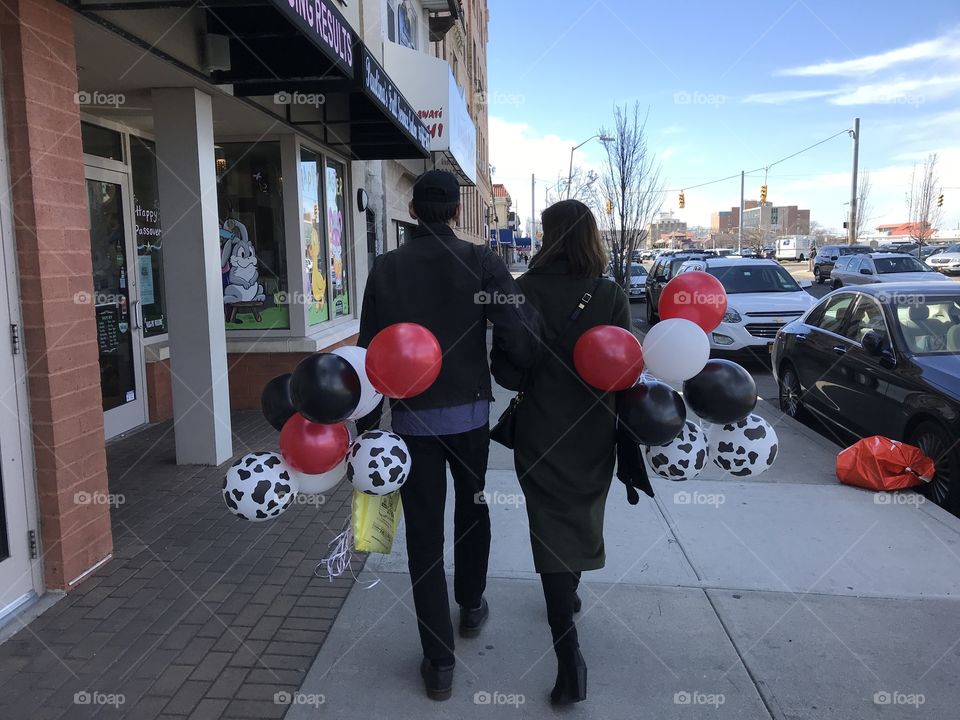 Young adults walking on the street holding balloons