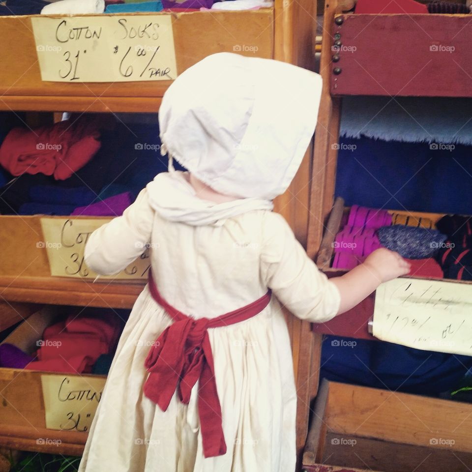 A child in 18th century garb explores the bins