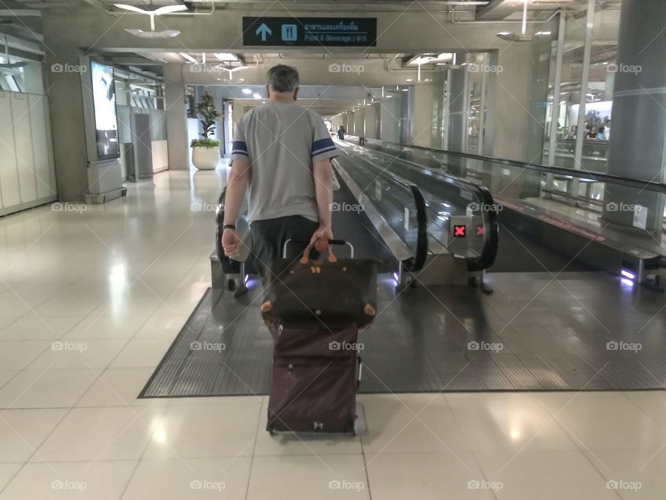 man who's going to travel with baggage walking in airport at city 