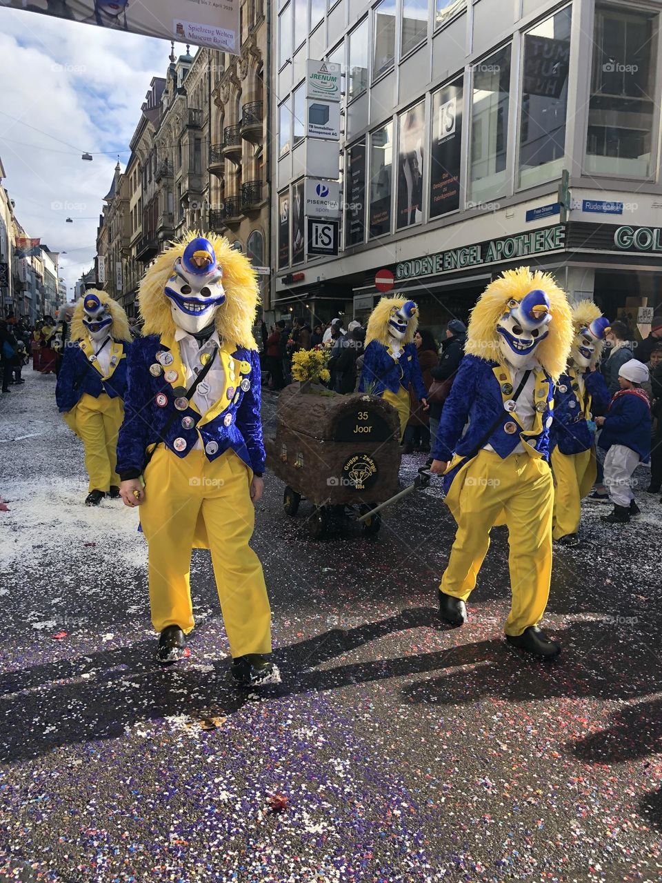 there is a crowd of people walking down the street in yellow clown costumes.  festive yellow costumes