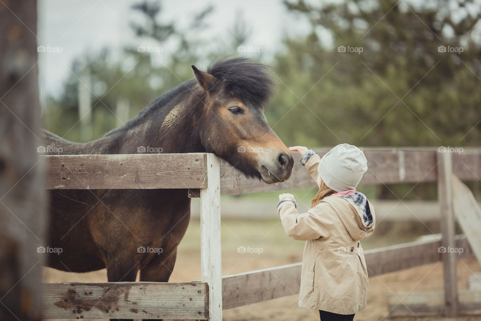 Little girl with pony, outdoor portrait 