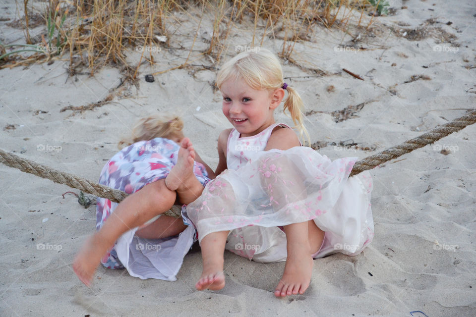 Two young sisters is posing for the camera on the beach on Majorca Spain.
This picture is on of three pictures were the both fal back in the sand.