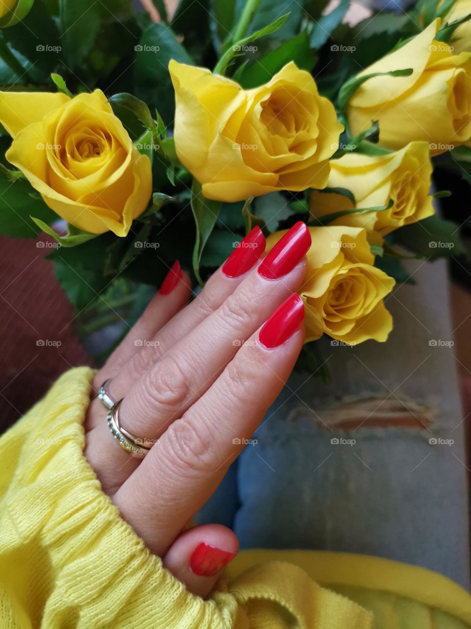 Red manicure, red nail polish. Hand with red manicure and yellow roses bouquet.