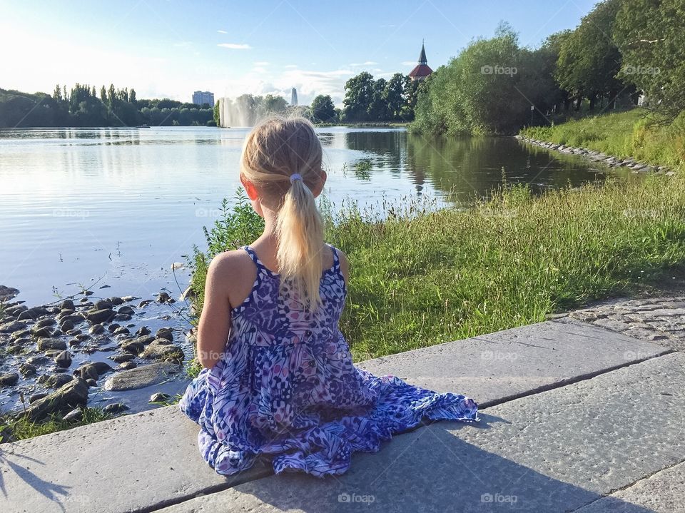 Littl girl is looking outvover a pawn at Pildammsparken in Malmö Sweden. The girl is six years old.