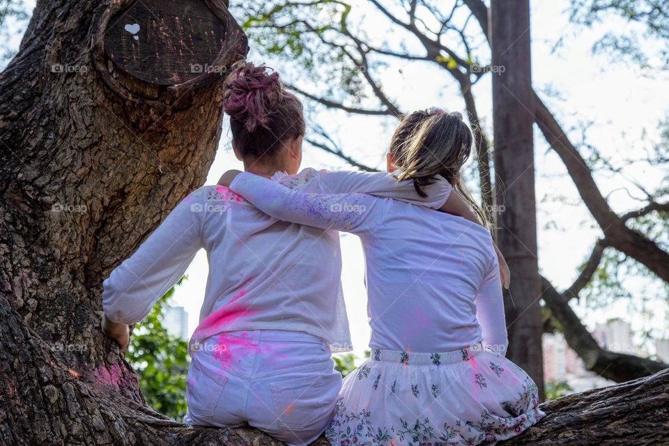 Two female friends sitting at the top of the tree