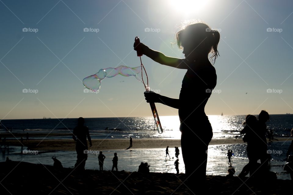 A girl on the beach making bubbles