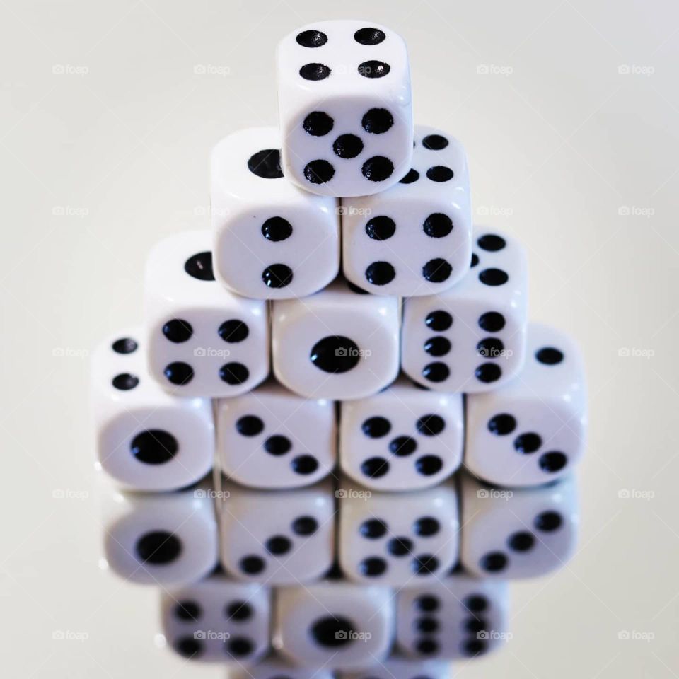 Dice stacked in the shape of a pyramid with mirror reflection