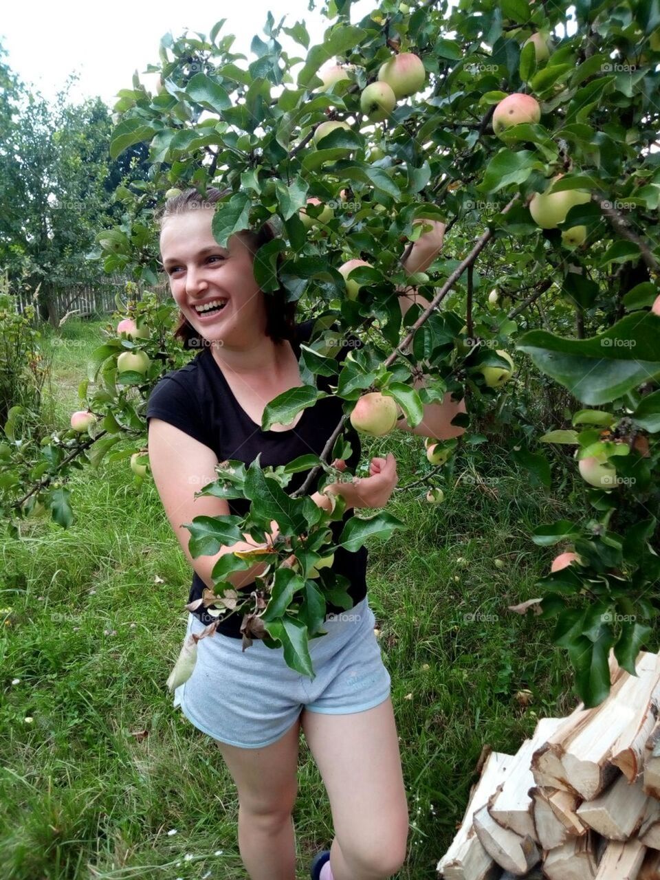 portrait of a village girl with short hair and a smile standing near a tree with apple fruits