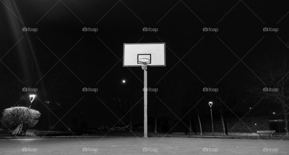 Desolate Basketball court in the night in a park, monochrome. Sign of an orphan world of a star