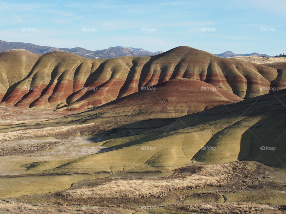 The incredible beauty of the red, gold, and browns of the textured Painted Hills in Eastern Oregon on a bright sunny day.