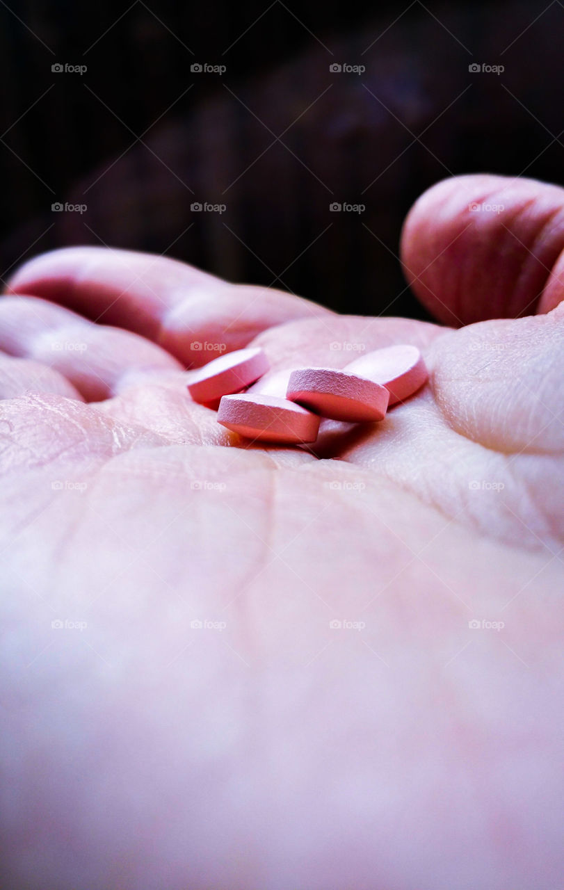 Hand holding pink pills
