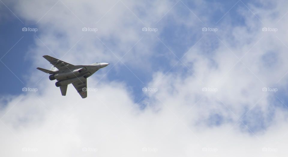 The plane is flying against the blue sky. Aerobatic figure, military aircraft.