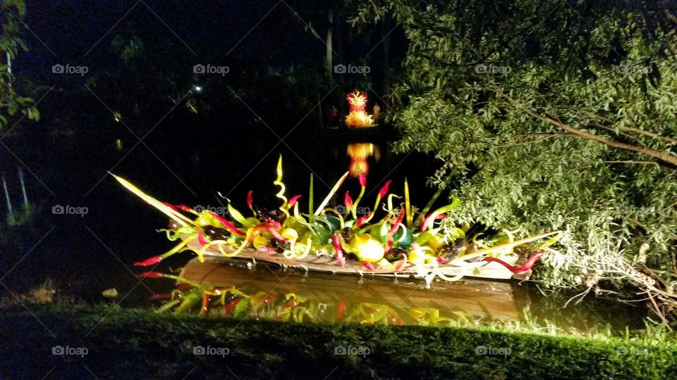 glass art in a boat reflecting in the water at night