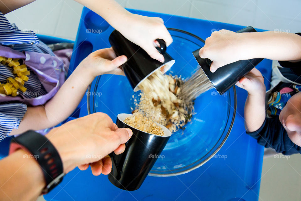 Creative play with kids - making and baking together at home. Kids and mom putting ingredients together.