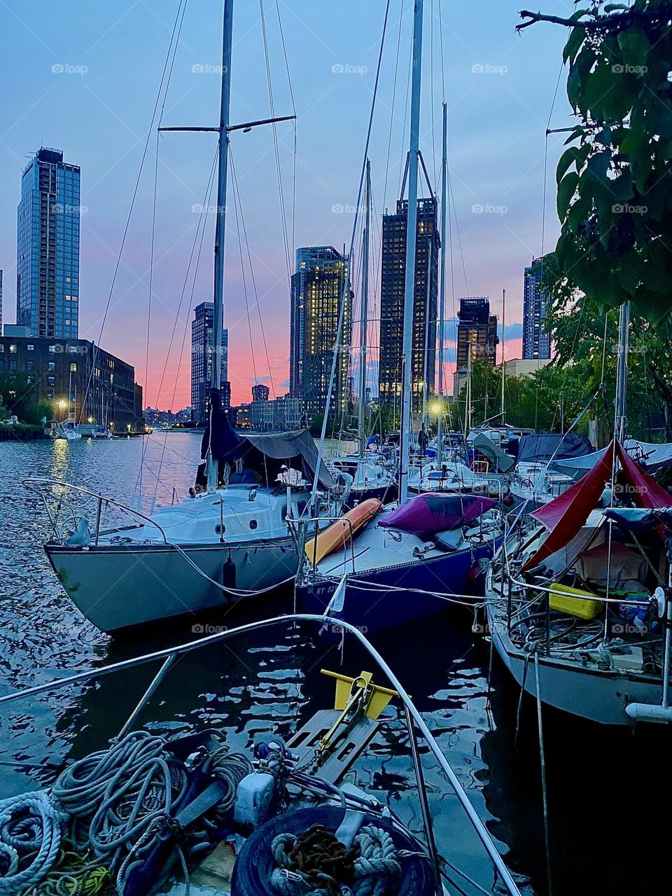 It’s twilight time here at „Newtown Creek“ by the „Pulaski Bridge“ in LIC, Queens. The sun is setting behind the horizon and gives the sky pink to magenta to purple hues. The boats are seen from aboard the „Salvation“. 2023. Hypnotic Productions