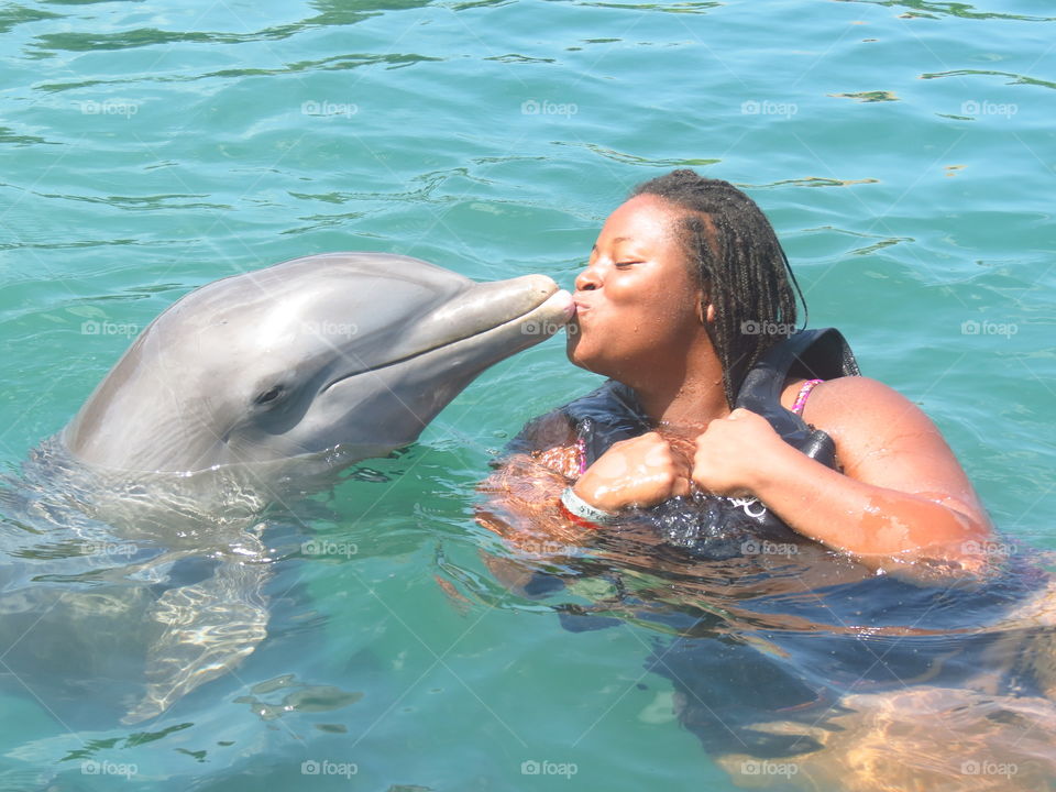 African woman kissing dolphin