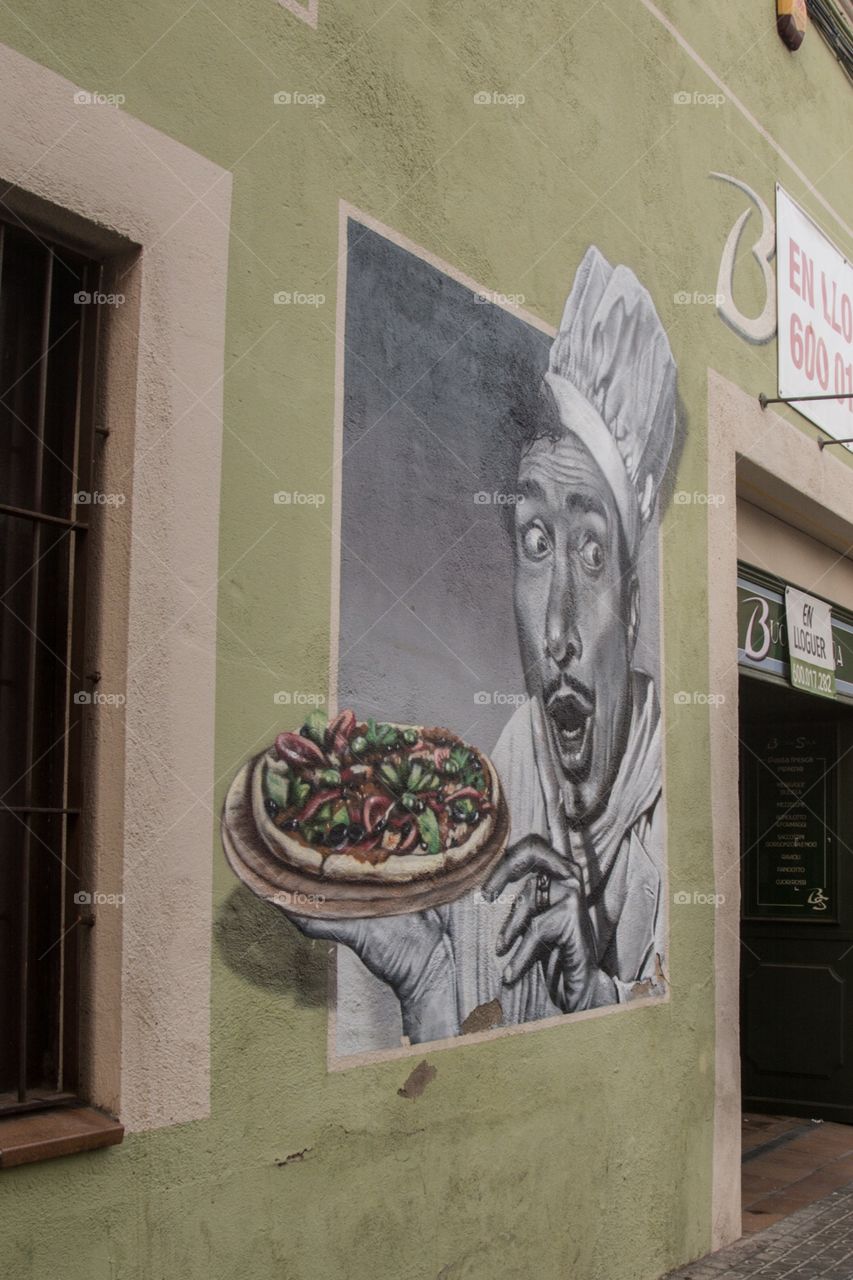 A pizza drawing on the wall in the streets of Spain