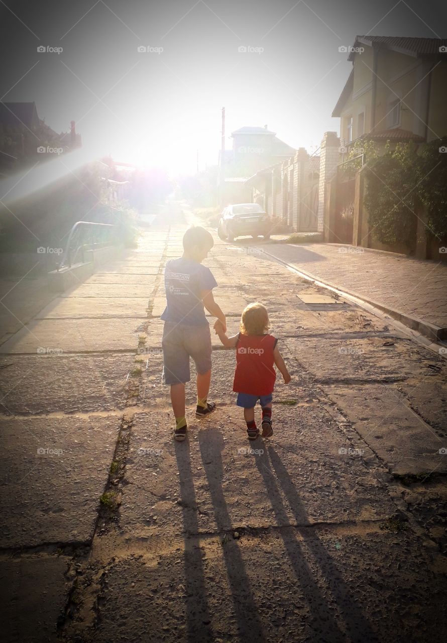 two boys walk along the street