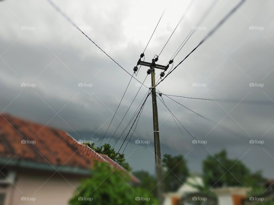 natural scenery of cloudy clouds that will rain accompanied by lightning, with electricity poles and house tiles