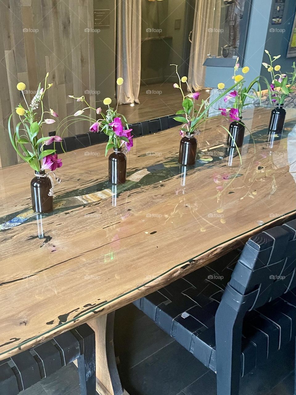 An elegant table setup at the Grand Bohemian Lodge in Greenville, SC. The table is adorned with an intricate design, showcasing detailed craftsmanship in its woodwork, complemented by simple yet tasteful flower displays.