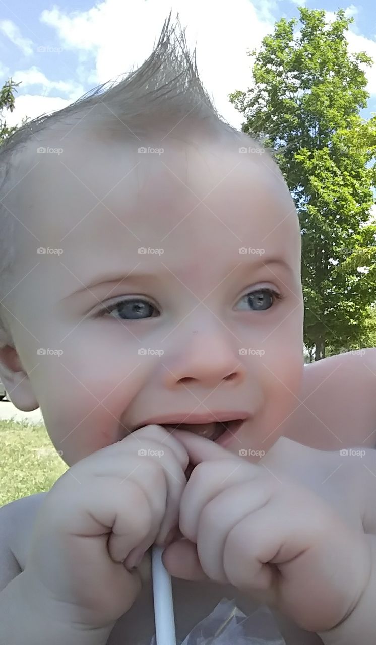 Chewing teething beautiful blue eyes baby boy at the beach.