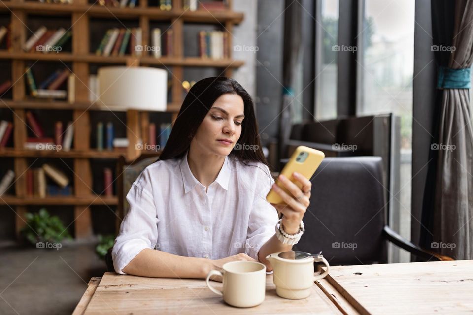 Woman using mobile phone in cafe 