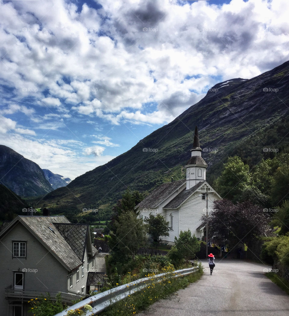 Woman in a red hat walking to church on a country road in Norway 