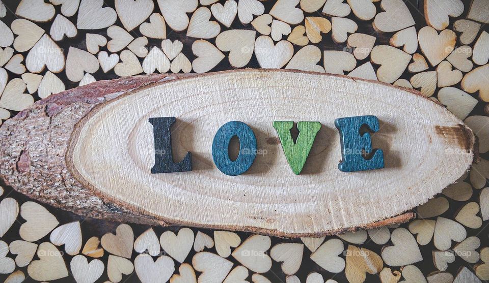 Wooden letters spell the word love, surrounded by wooden hearts of varying sizes 