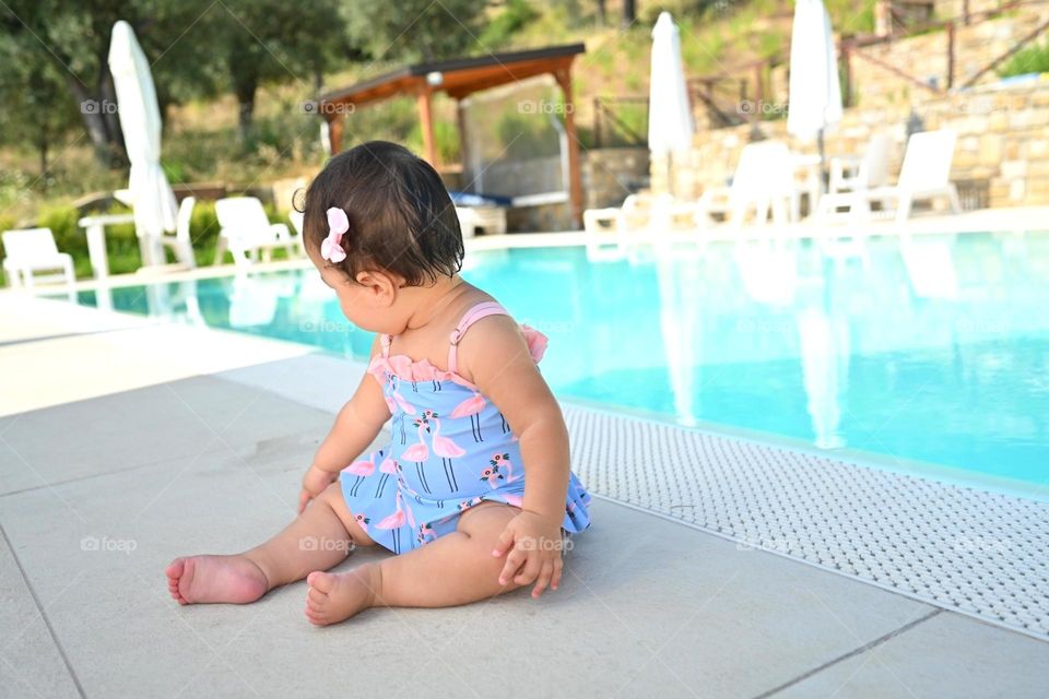 little girl in a swimsuite by the pool