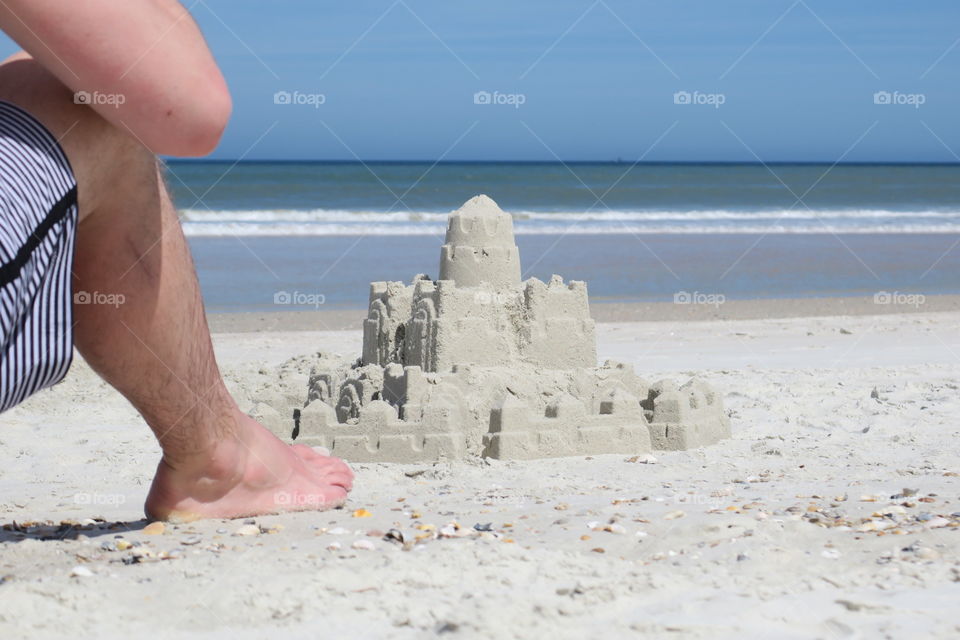 Sandcastle by the Ocean. Beach Goer Lounges by Sand Castle on a Sunny Florida Beach.