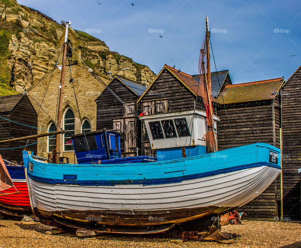 A fishing boat sits amidst the fisherman’s hut, under the cliff at Hastings, UK 