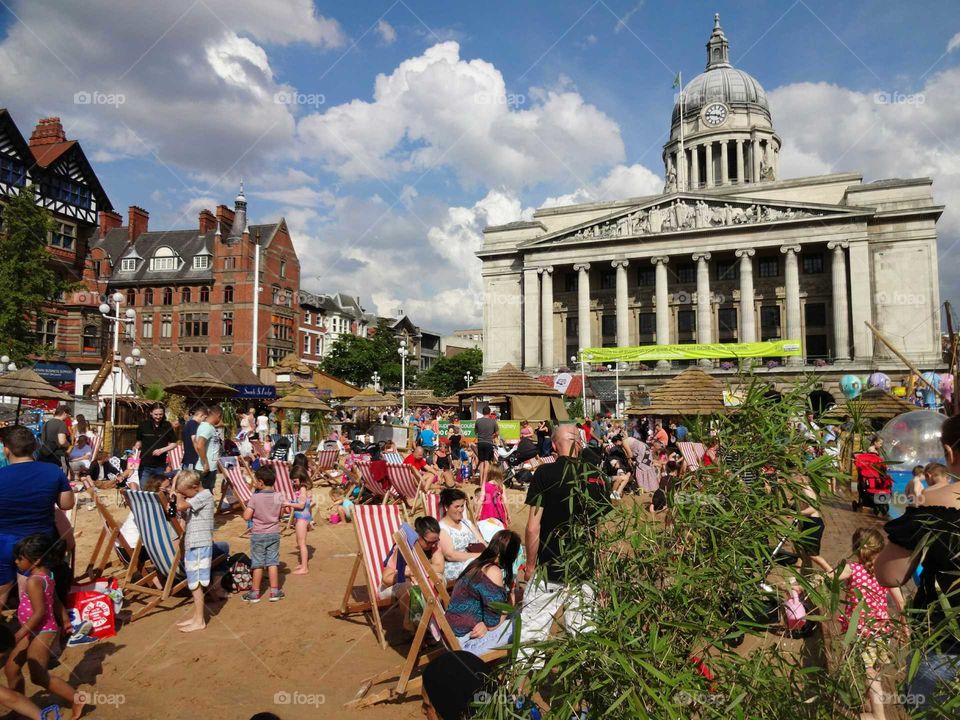 People enjoying good weather on the artificial beach in the Old Market Square with the Council House in the background, Nottingham, England, UK