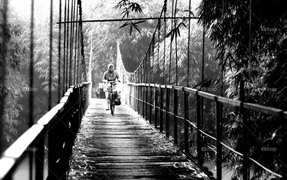 Senior woman cycling on bridge