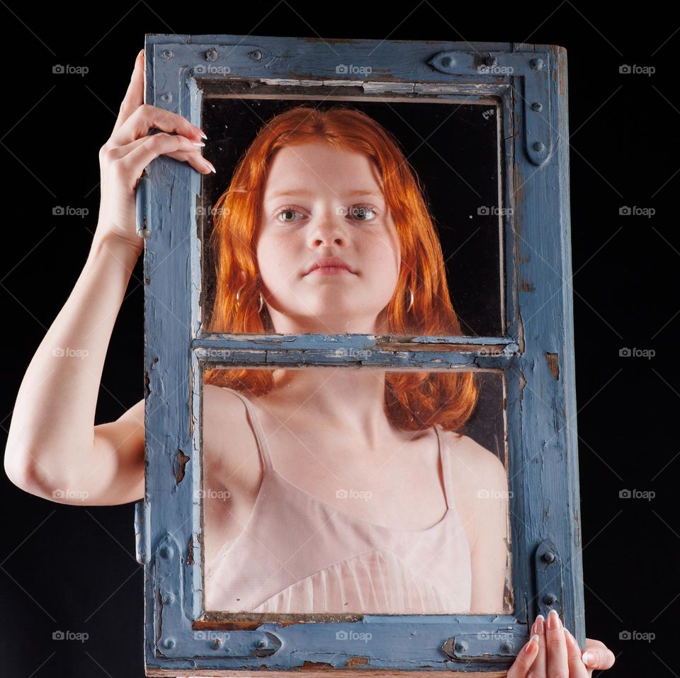 young teen,red hair ,very good modeling with a window in her hands .Creative photography