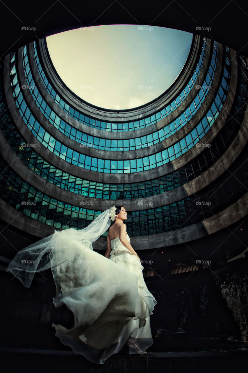 Bride in wedding gown against building wall