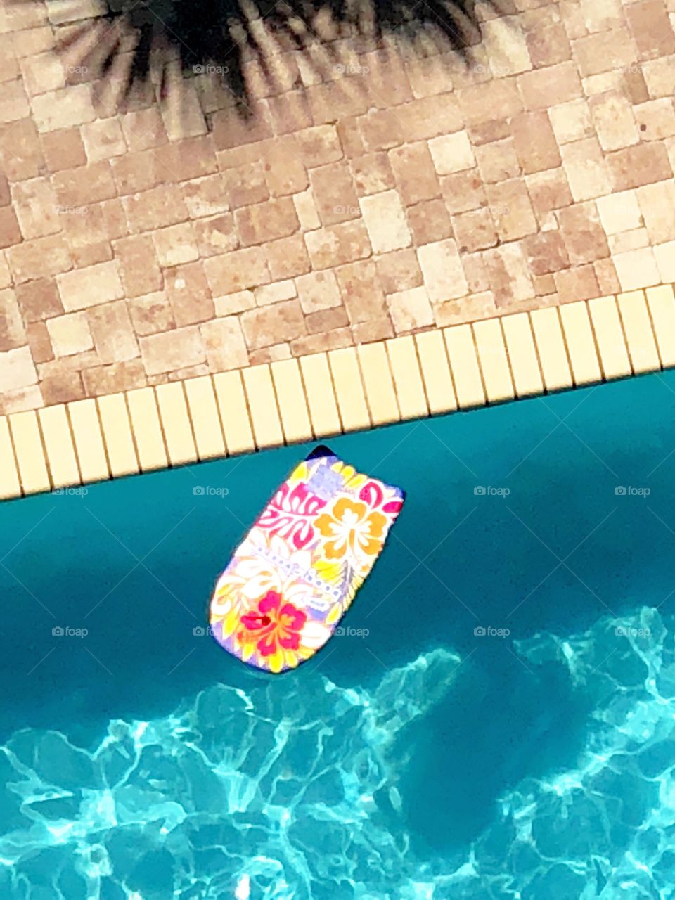 A tropical boogie board floating in a swimming pool. 