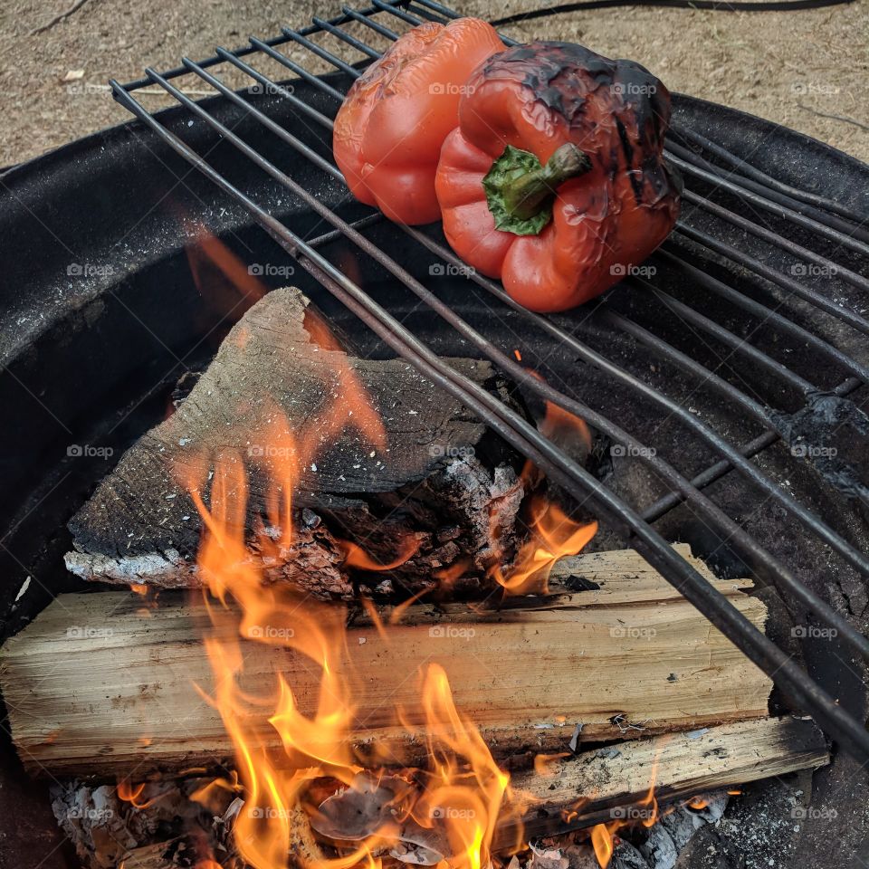 Roasting red peppers over a fire.
