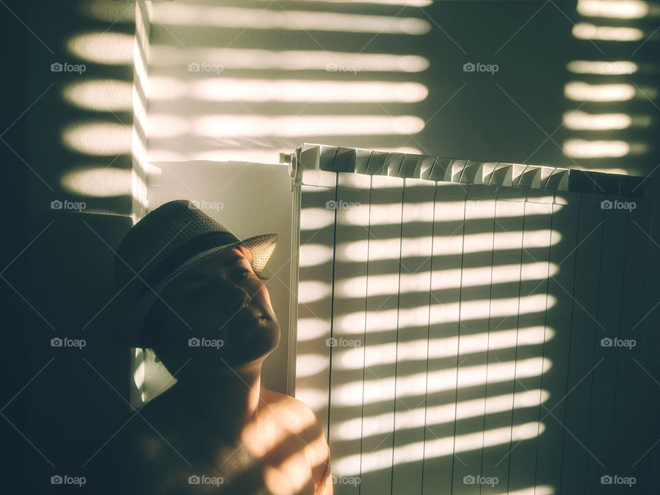 Play of light and shadow.  Portrait of a young woman at home against a background of a white wall with shadows.