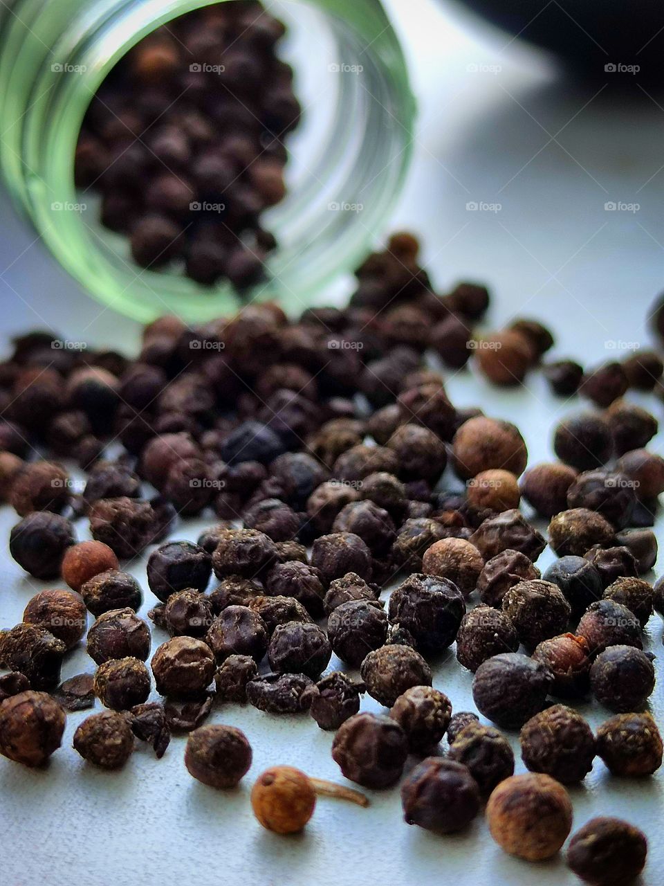 Spices. Black allspice peas and a transparent neck of the bottle