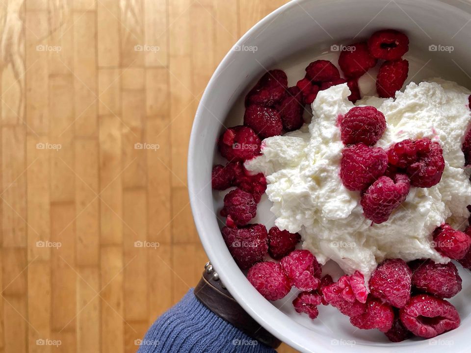 Close-up of raspberries on yogurt in a white bowl