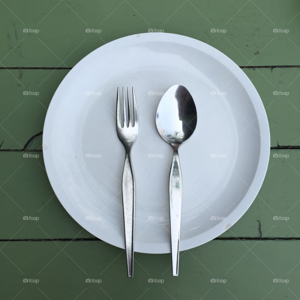 Spoon and fork on plate over the table