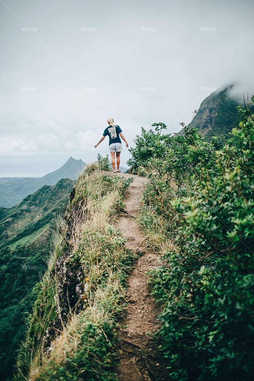 Girl hiking dangerous cliff in Hawaii.