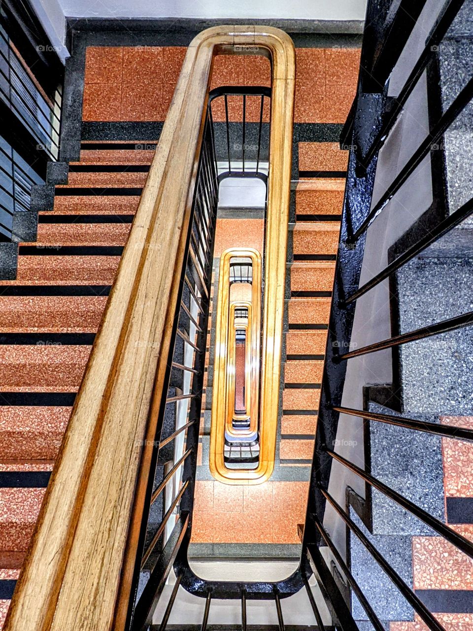 vertical view down the centre of a winding marble staircase