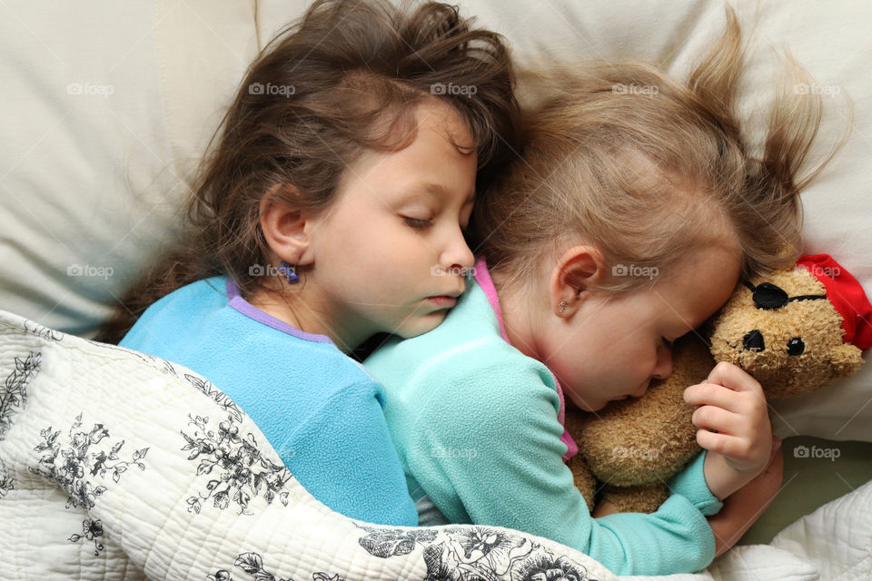 Two young sisters hugging and sleeping