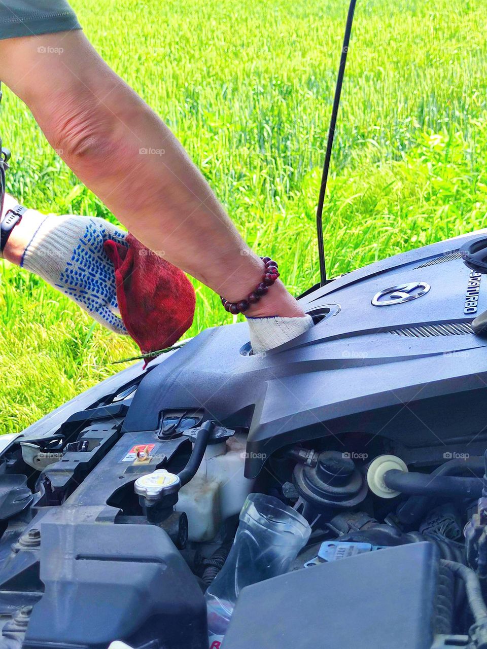 Open car hood. Man's hands in gloves check the oil level